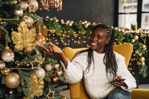 young-beautiful-african-woman-using-her-phone-home-decorated-christmas-season-scaled.jpg