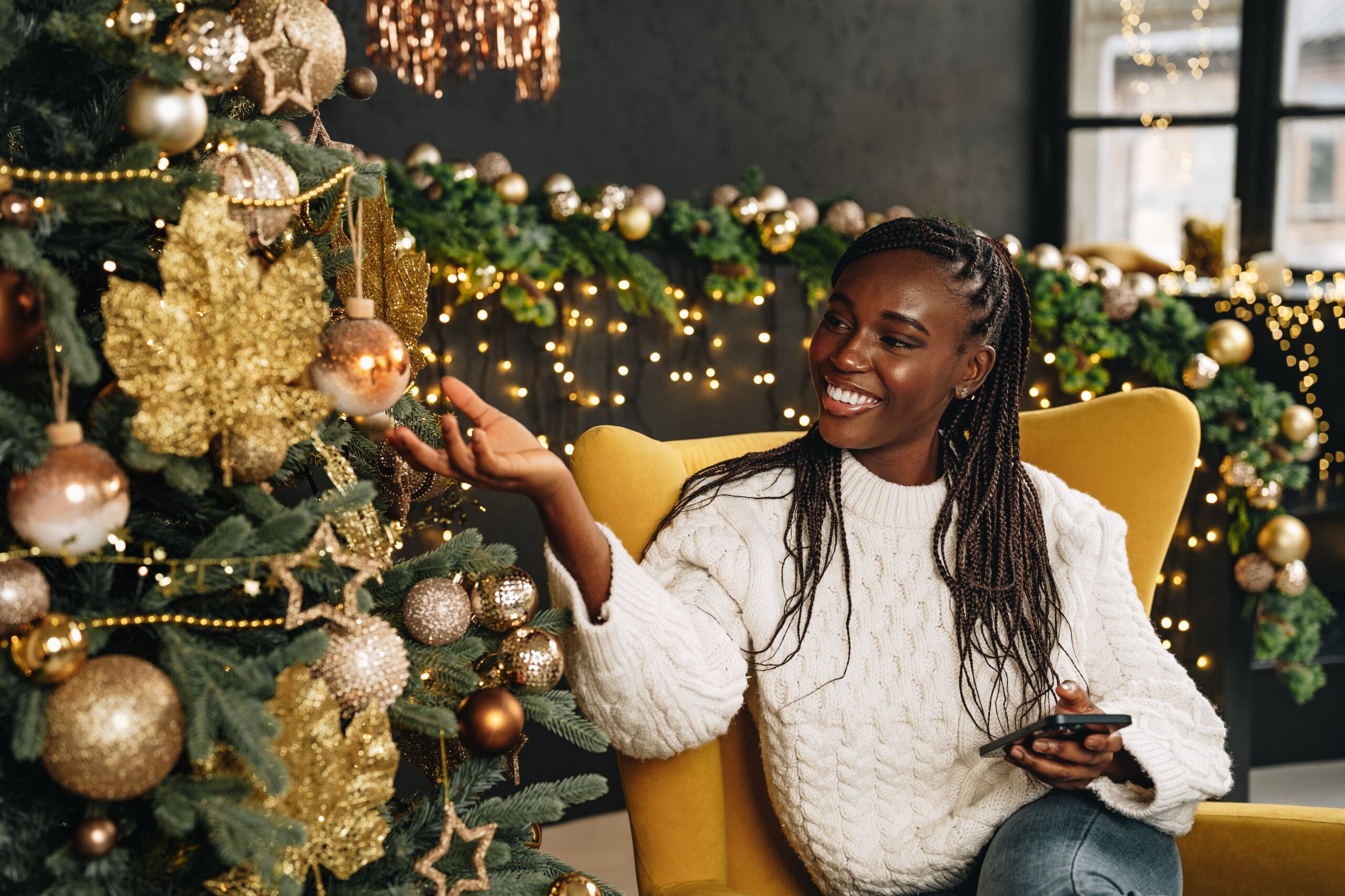 young-beautiful-african-woman-using-her-phone-home-decorated-christmas-season-scaled.jpg