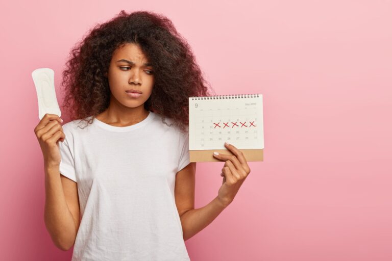photo-discontent-lovely-curly-haired-woman-looks-calendar-with-marked-pms-days-scaled.jpg