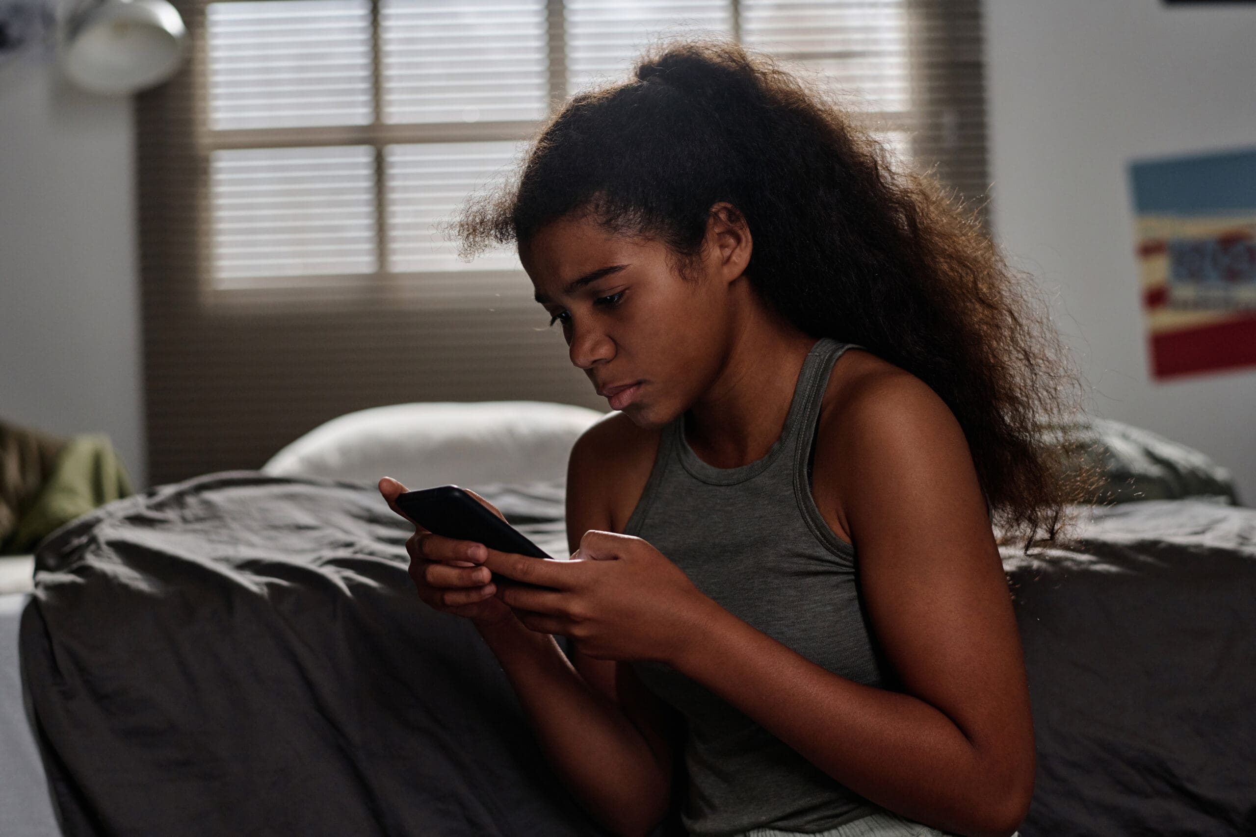 unhappy-teenage-girl-grey-vest-looking-smartphone-screen-scaled.jpg