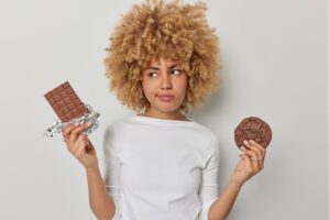 thoughtful-confused-woman-chooses-chocolate-cookie-has-sweet-tooth-dressed-casual-sweater-keeps-diet-feels-temptation-eat-delicious-harmful-food-isolated-white-background-scaled.jpg